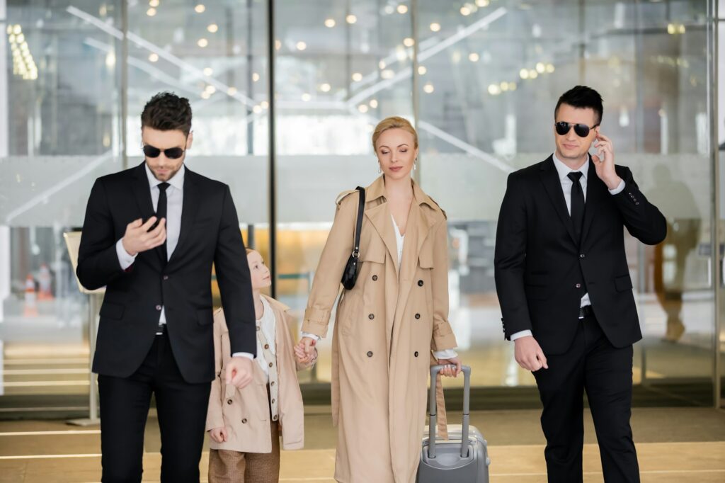 personal security concept, two bodyguards in suits and sunglasses protecting blonde woman